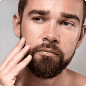 Man with a beard touching his face and inspecting his skin