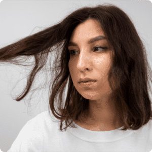 Woman with damaged, frizzy hair examining its condition.